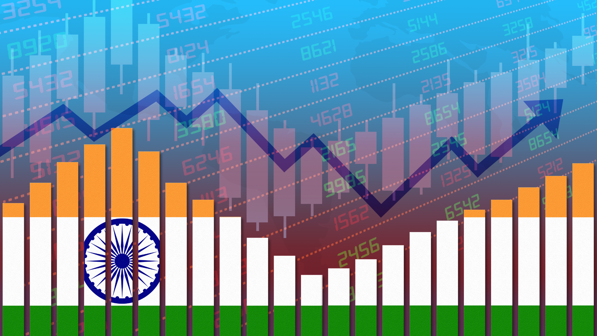 A graphic of the Indian flag in orange, white and green represented as a falling and rising stocks chart, with a real red and green stock indicator chart in the background and a growth projection arrow following the shape of the graph. The Indian national emblem is displayed at the left of the graphic.